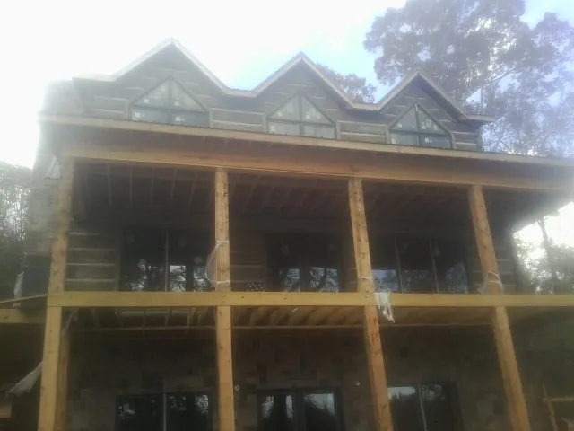Dormers and porch framing on a large log home under construction — Roof Coating work by our crew in Maryknoll