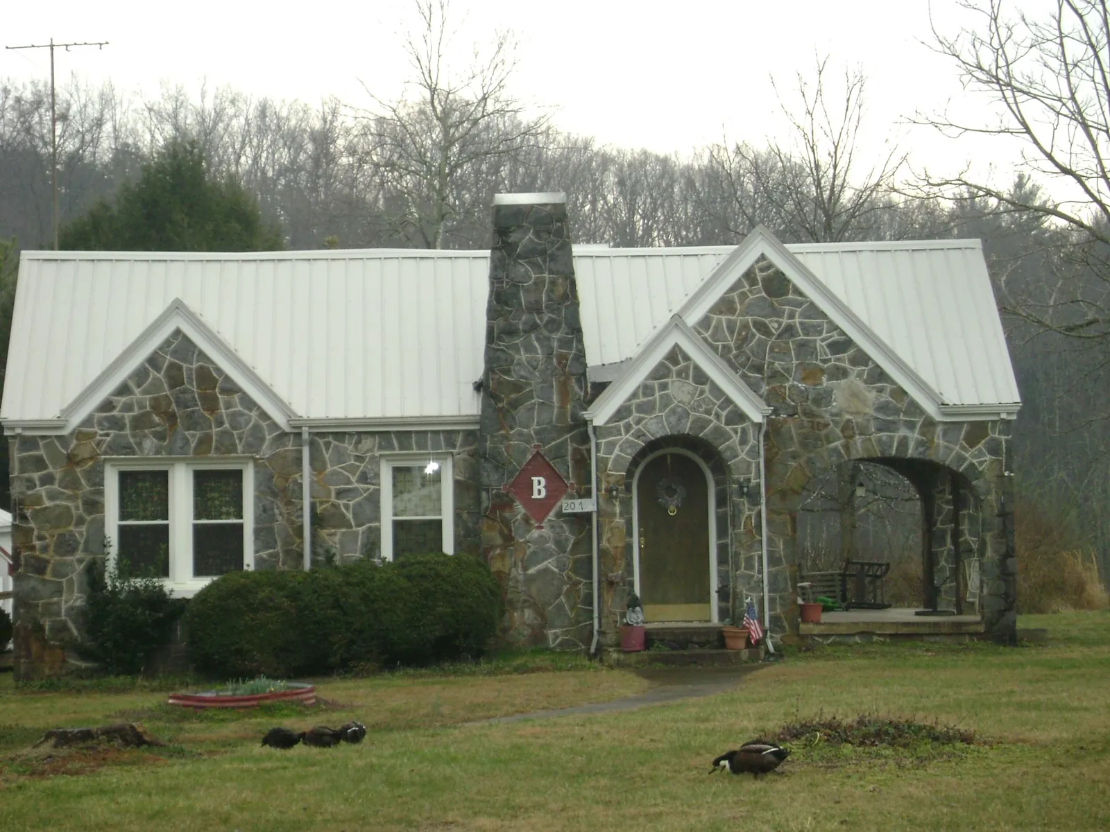 White metal roof on a stone cottage with steep gables in Maryknoll