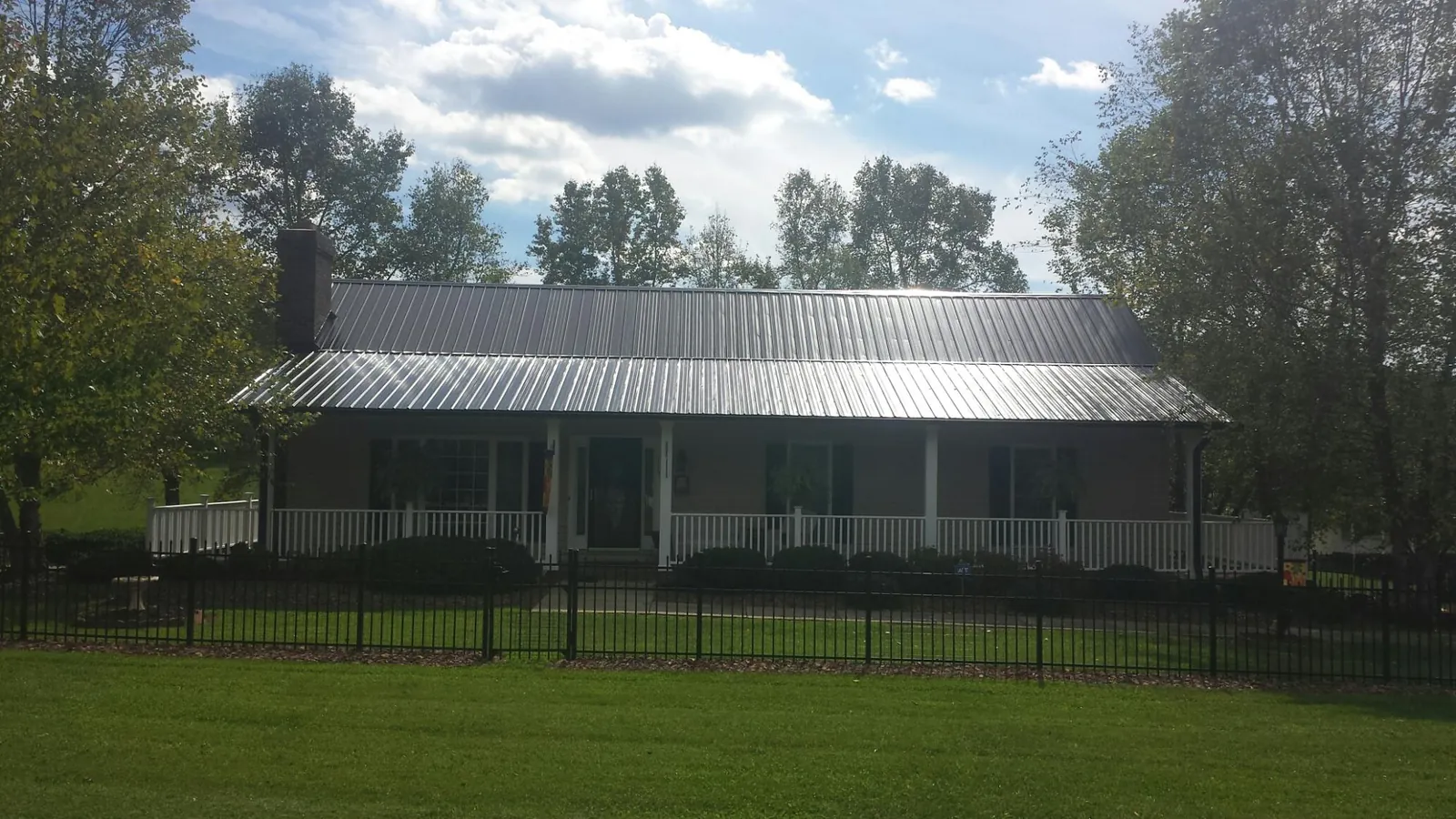 Gray metal roof on a brick ranch with a full width front porch — Gutter Guard Installation work by our crew in Maryknoll