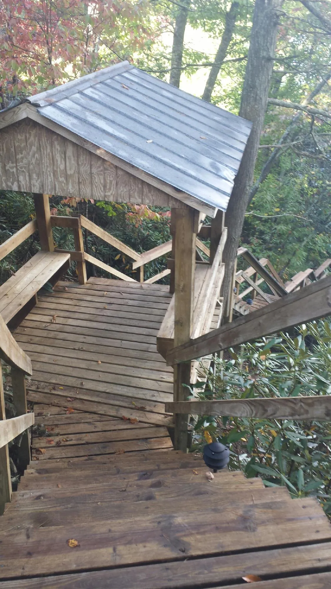 Metal roofed shelter over wooden steps on a wooded walkway — Skylight Repair & Installation work by our crew in Maryknoll