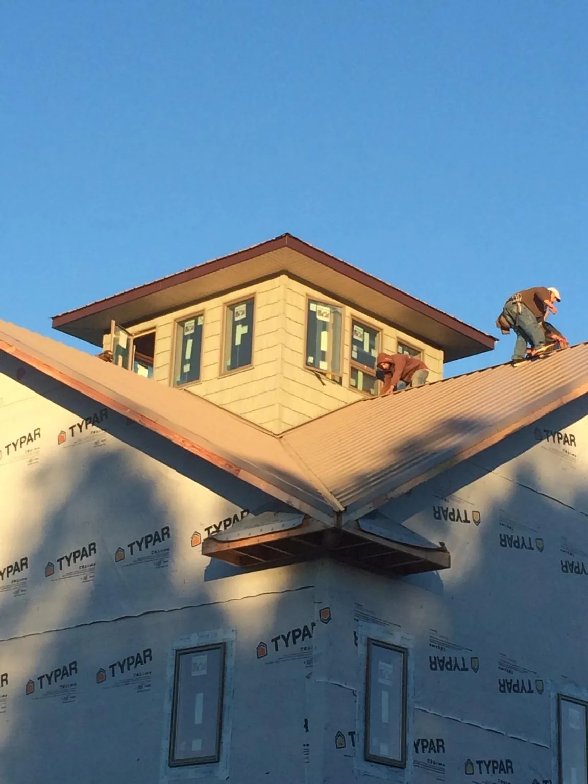 Roofers working around a rooftop cupola on a new metal roof at sunset — Roof Waterproofing in Maryknoll by Roofing Brothers